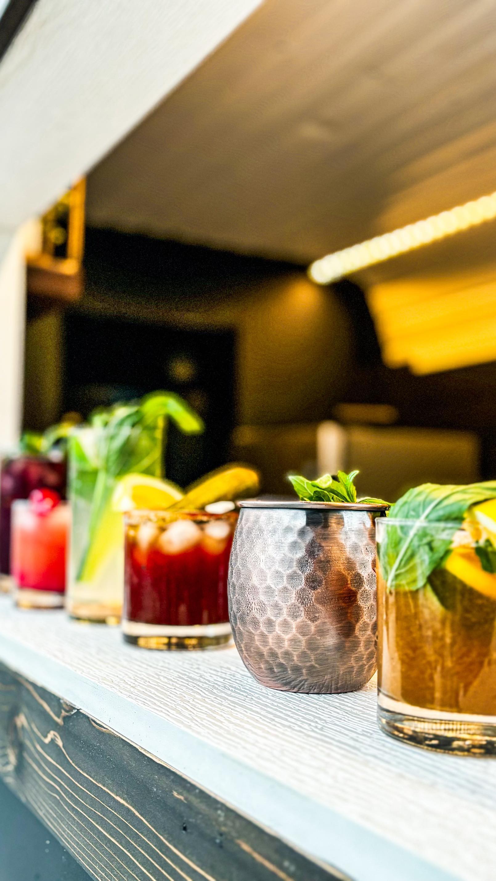 Colourful cocktails with citrus and mint lined up on the bar