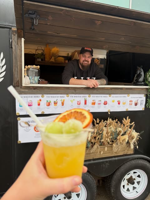 Matt smiling behind the bar with a cocktail in the foreground