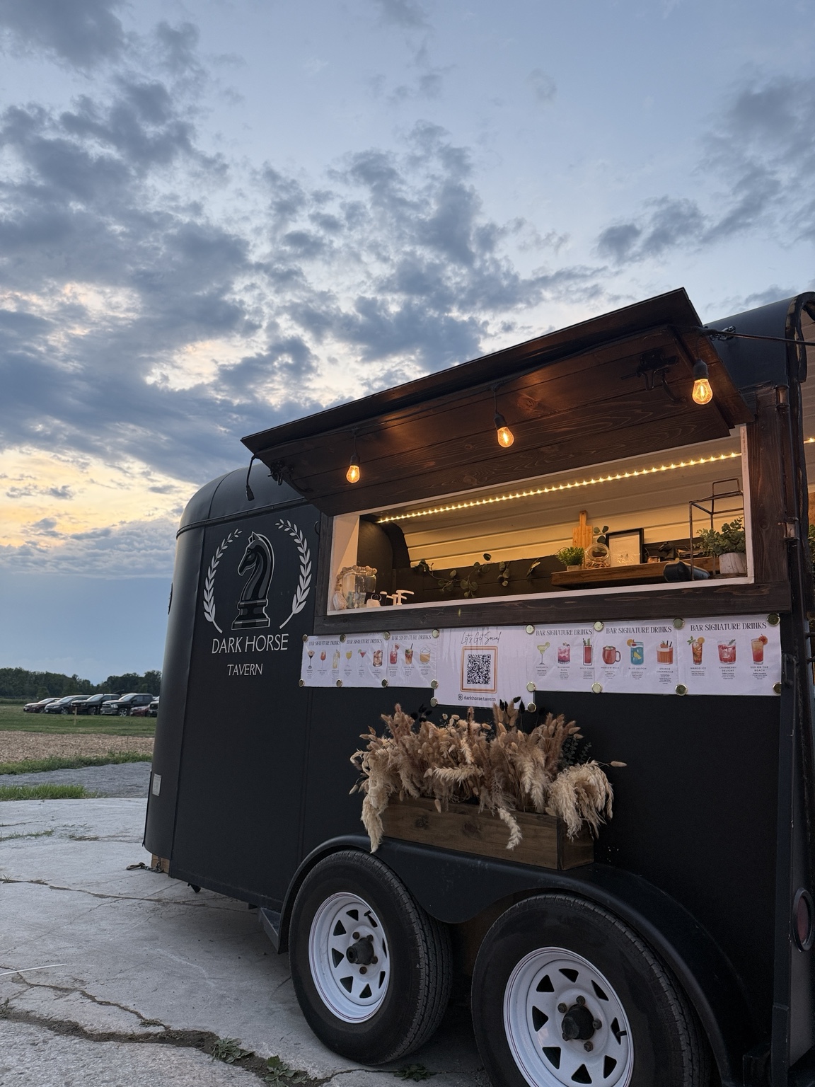 The Dark Horse Tavern trailer glowing beneath a dramatic sunset sky