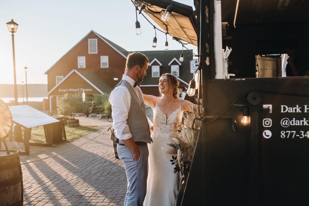 A bride and groom sharing a quiet moment beside the Dark Horse Tavern trailer at sunset